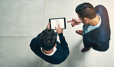 Buy stock photo High angle shot of two businessmen working together on a digital tablet in an office
