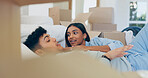 Couple, talk and relax after move to new home by lying on sofa in living room with boxes. Married people, bonding and ready for future with property investment, mortgage loan or sale in real estate