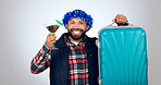 Portrait, cocktail and suitcase for travel with a man in studio on a gray background for holiday or vacation. Smile, alcohol and luggage with a happy young tourist drinking in celebration of a trip