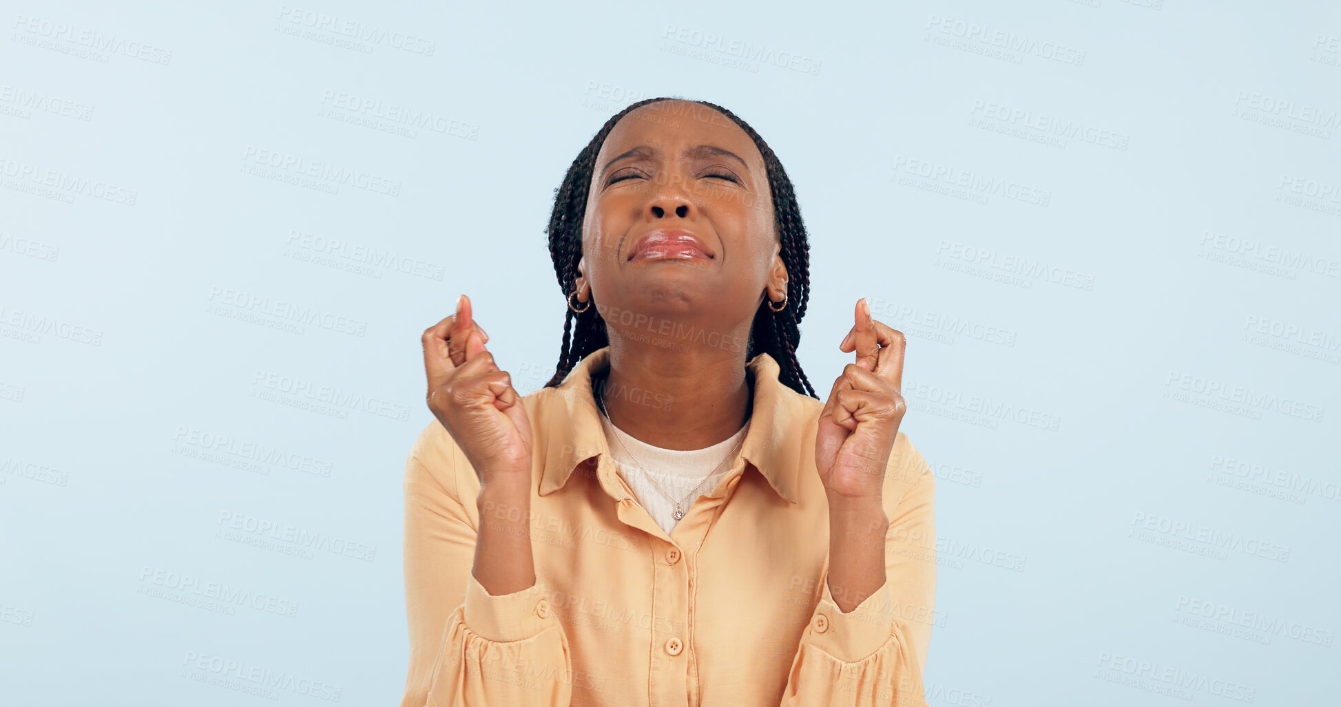 Buy stock photo Nervous, woman and hope with fingers crossed in studio for lucky news, feedback and waiting with anxiety on blue background. African model, worry and stress with hand sign for wish, praying and emoji