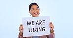 Recruitment, smile and portrait of woman in a studio with a hiring sign, poster or board for job. Happy, employment and face of young Asian female person advertising a career offer by blue background