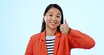 Portrait, smile and thumbs up with a business asian woman in studio on a blue background or support. Thank you, winner and emoji with a happy young employee in celebration of a goal or target