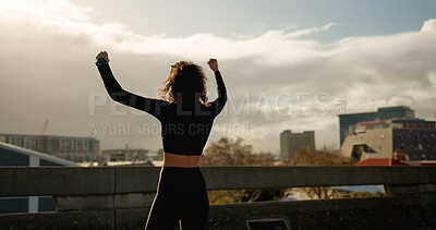 Woman, fist pump and winning in city for fitness achievement, workout or outdoor training success. Rear view of female person, runner or athlete in celebration for goals or victory in an urban town