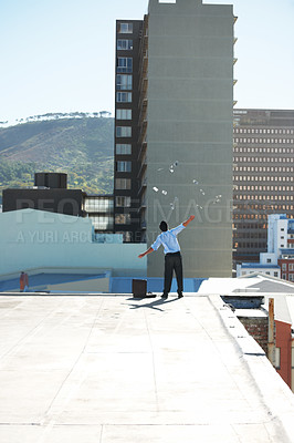 Buy stock photo Back, financial freedom and money rain with a man in the city, throwing cash during a summer day. Finance, success or raining dollars with a business person on the roof of a building in an urban town