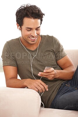 Buy stock photo A handsome young man sitting on his sofa and listening to music on his mp3 player
