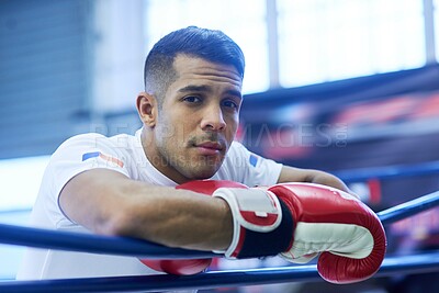 Buy stock photo Portrait of a young man leaning on the ropes while standing inside a boxing ring