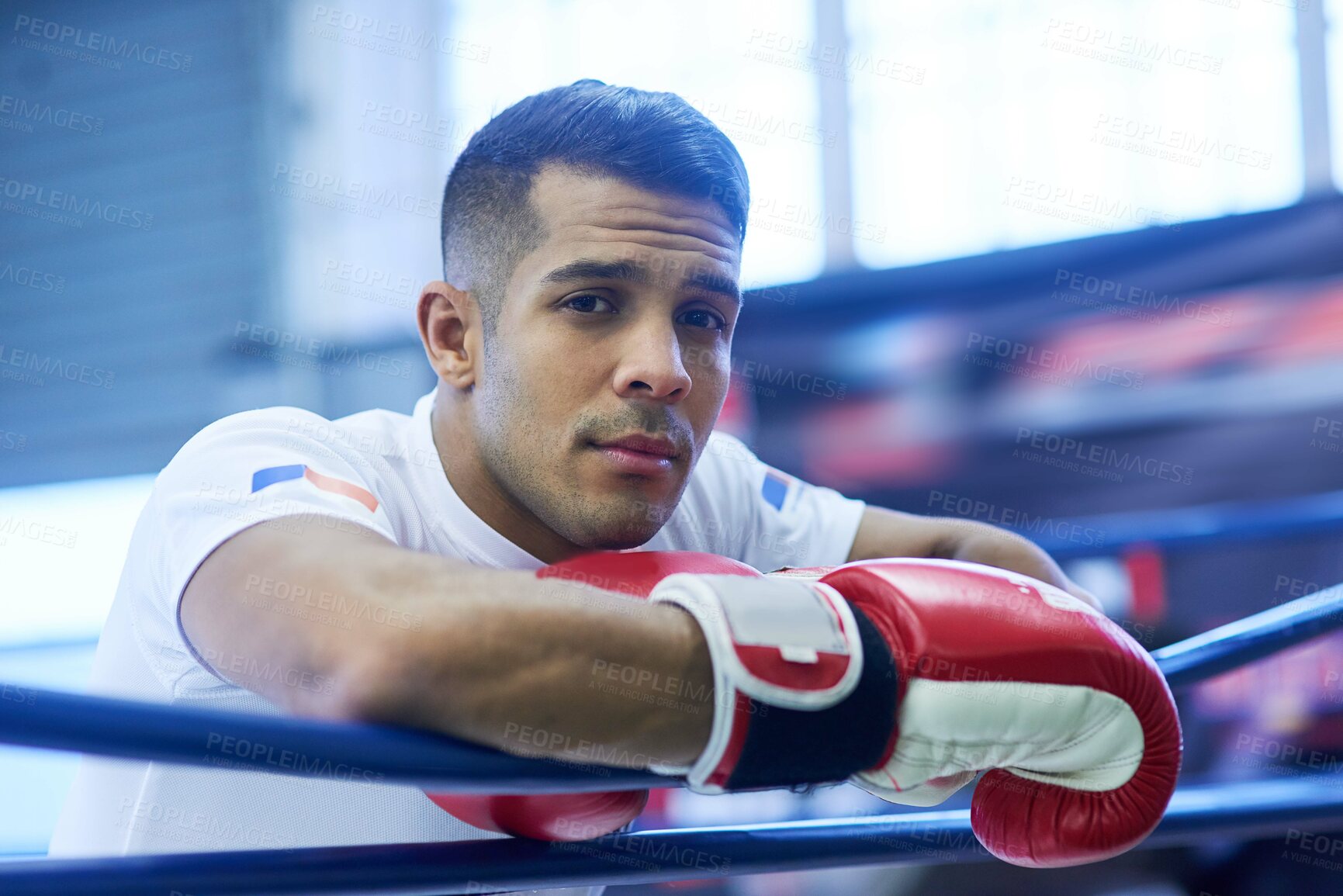 Buy stock photo Portrait of a young man leaning on the ropes while standing inside a boxing ring