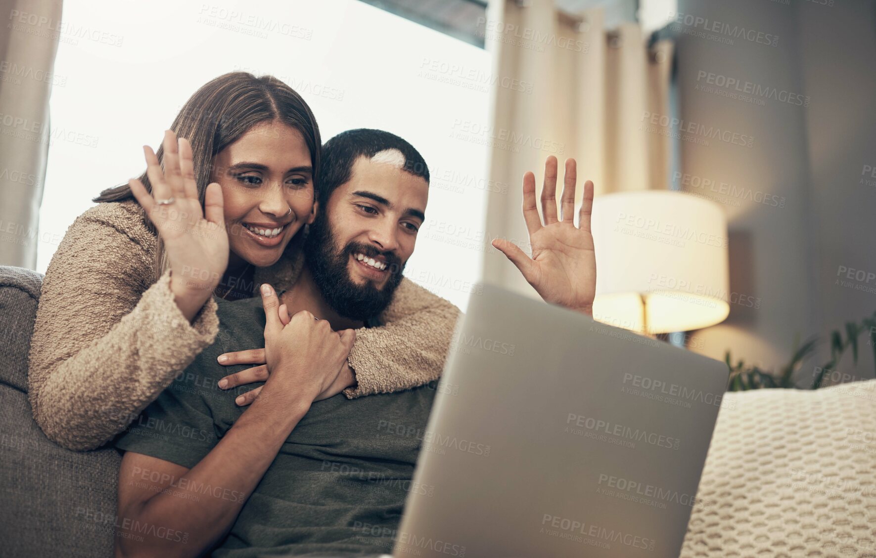 Buy stock photo Shot of a young couple using a laptop to make a video call on the sofa at home