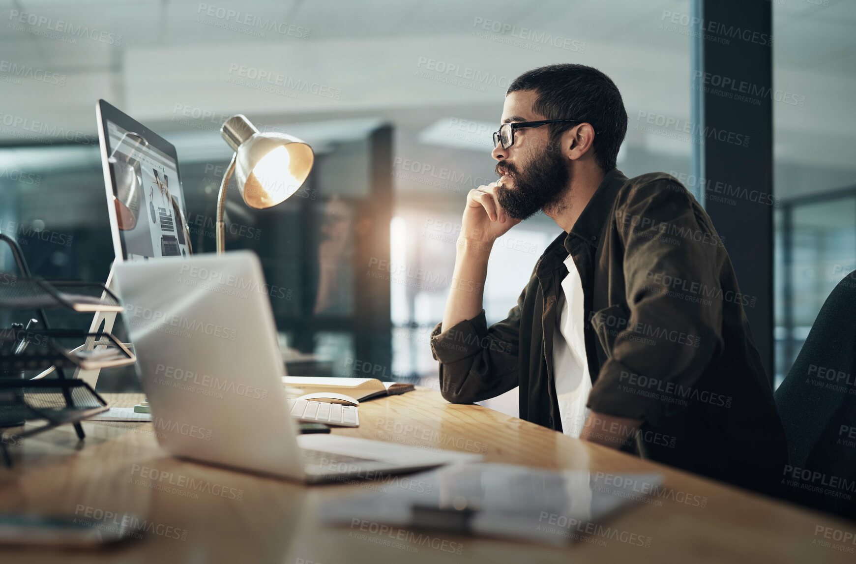 Buy stock photo Shot of a young businessman using a computer during a late night in a modern office