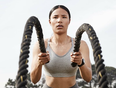 Buy stock photo Shot of an athletic young woman doing heavy rope training outside