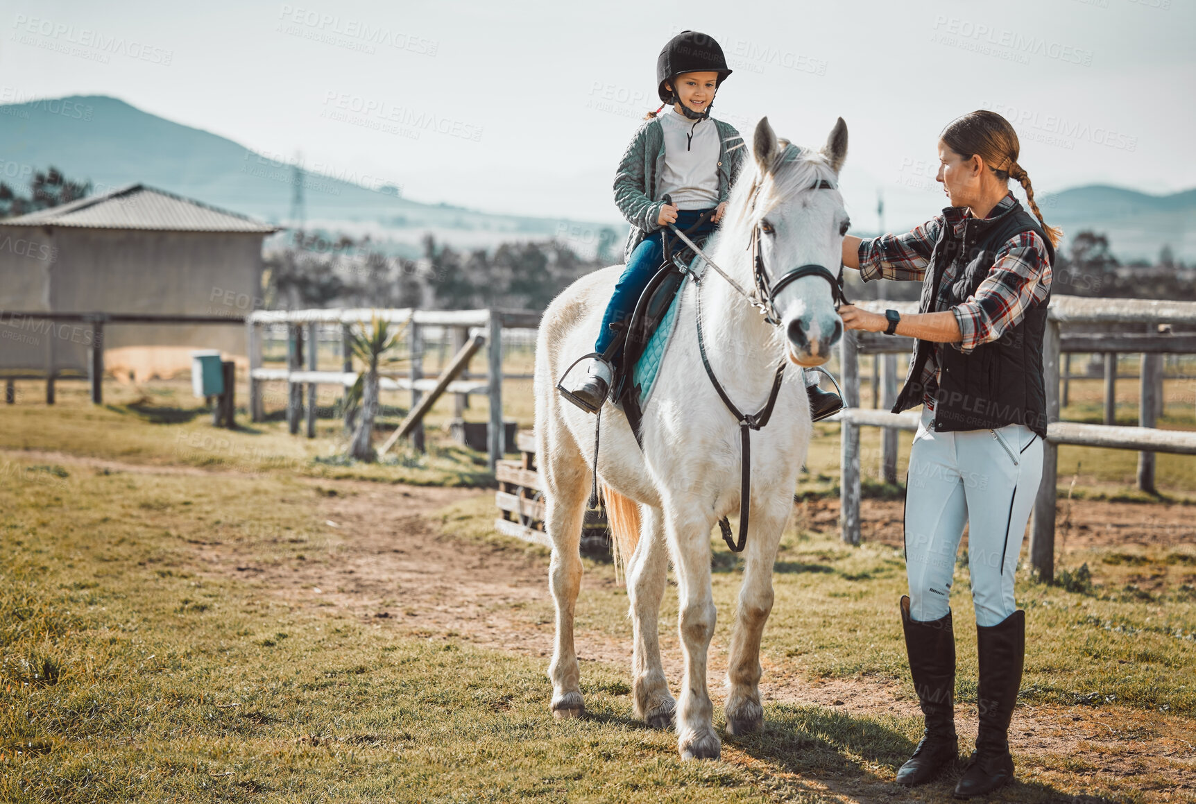 Buy stock photo Woman leading girl on horse, ranch and equestrian sports, lady, child and animal walking on field. Countryside lifestyle, rural nature and farm animals, mother teaching happy kid to ride pony in USA.