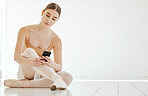 Phone, dance and space with a ballerina on the floor of a studio for social media or communication. Ballet, mockup or networking app with a serious young dancer typing a text message on her mobile