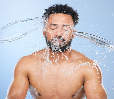 Buy stock photo Black man, water splash and washing in skincare for cleaning, hygiene or grooming against a blue studio background. Face of African male person, model and aqua for body hydration, shower or skin wash