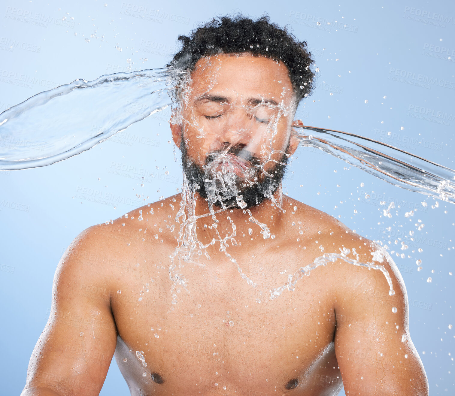 Buy stock photo Black man, water splash and washing in skincare for cleaning, hygiene or grooming against a blue studio background. Face of African male person, model and aqua for body hydration, shower or skin wash