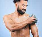 Shower, washing and man with sponge and soap for cleaning, hygiene and skincare on blue background. Dermatology, bathroom and person with splash, foam and cosmetics for wellness or health in studio