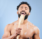 Shower, brush and man singing in studio for cleaning, wellness or morning routine on blue background. Bathroom, karaoke and male model having fun with body scrubber, cosmetics or luxury washing