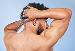 Man, shower back and splash in studio with water, wash or hygiene with self care by blue background. Person, guy and muscle with hair, wellness or health for skin, natural dermatology and body