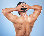 Man, shower back and wash in studio with water, splash or hygiene with self care by blue background. Person, guy and muscle with hair, wellness or health for skin, natural dermatology and body