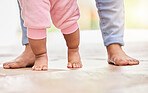 Walking, learning and feet of parent and baby on floor for child development, growth and first steps at home. Family, childhood and closeup of toddler for bonding, relationship and balance in nursery