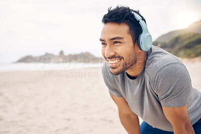 Buy stock photo Break, beach and man workout to relax with a smile after cardio exercise. Fitness, jog and healthy athlete or male person rest in natural ocean with headphones for music and physical wellness