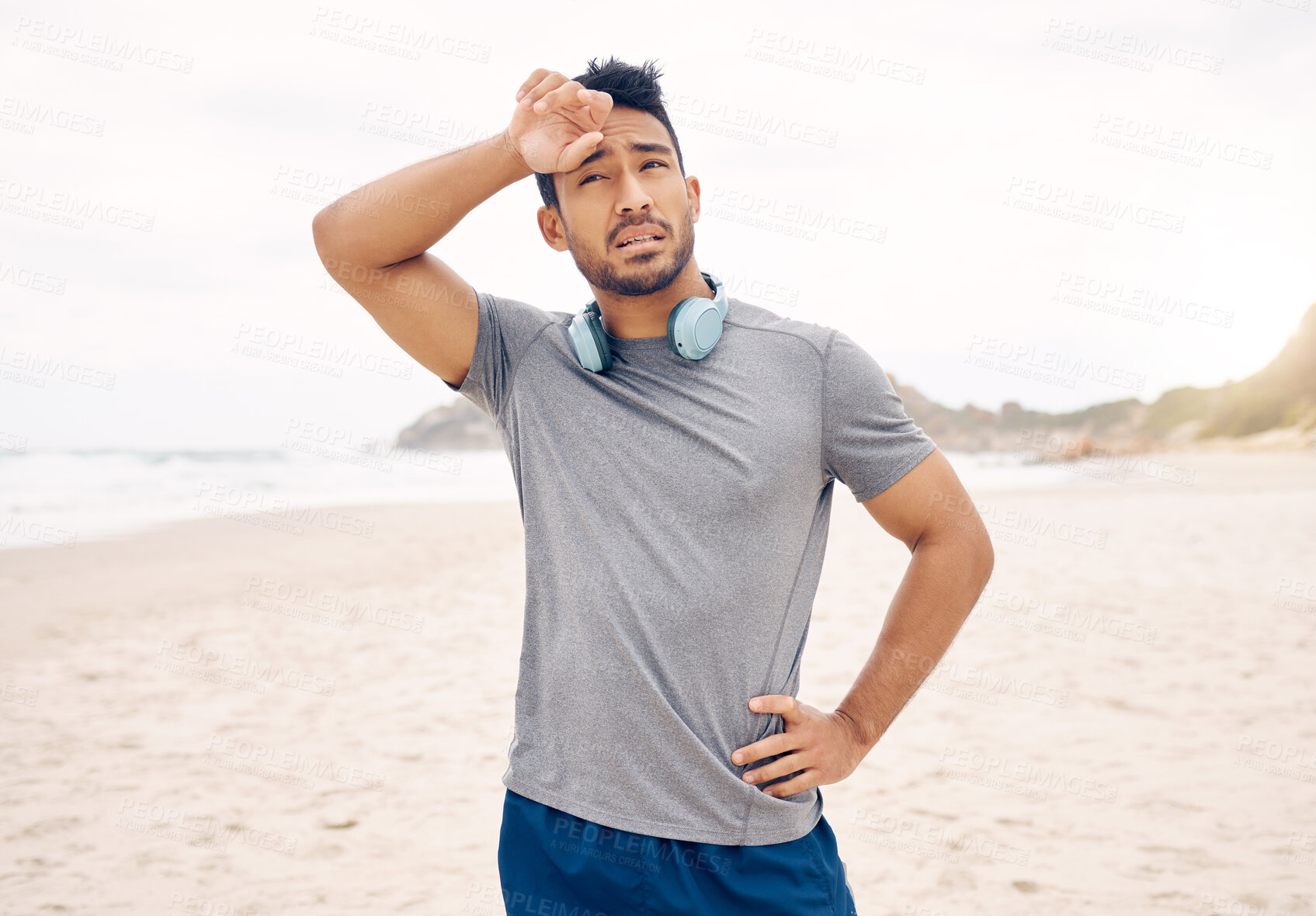 Buy stock photo Tired, fitness and man on a beach taking a break after workout for active lifestyle. Exercise, natural ocean and male person with fatigue or exhausted after training run and wiping sweat after jog