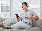 Happy, headphones and phone with credit card and woman at home with purchase, music and smile. Online shopping, tech and internet with banking and audio with mobile by a sofa with digital buying