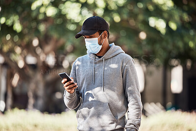 Buy stock photo Man looking at phone in nature park, wearing face mask to prevent risk of covid and reading a text message online. Guy standing in garden outside, typing on social media and looking for gps location