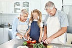 Grandparents, girl child in kitchen and cooking healthy food with vegetables on cutting board for happy family lunch at home. Natural, organic nutrition and clean diet for senior people in retirement