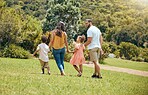 Family, kids and walking in the park for bonding, fun and care in summer outside. Mother, father and parents playfully walk with children, son and daughter siblings in a garden for bond 