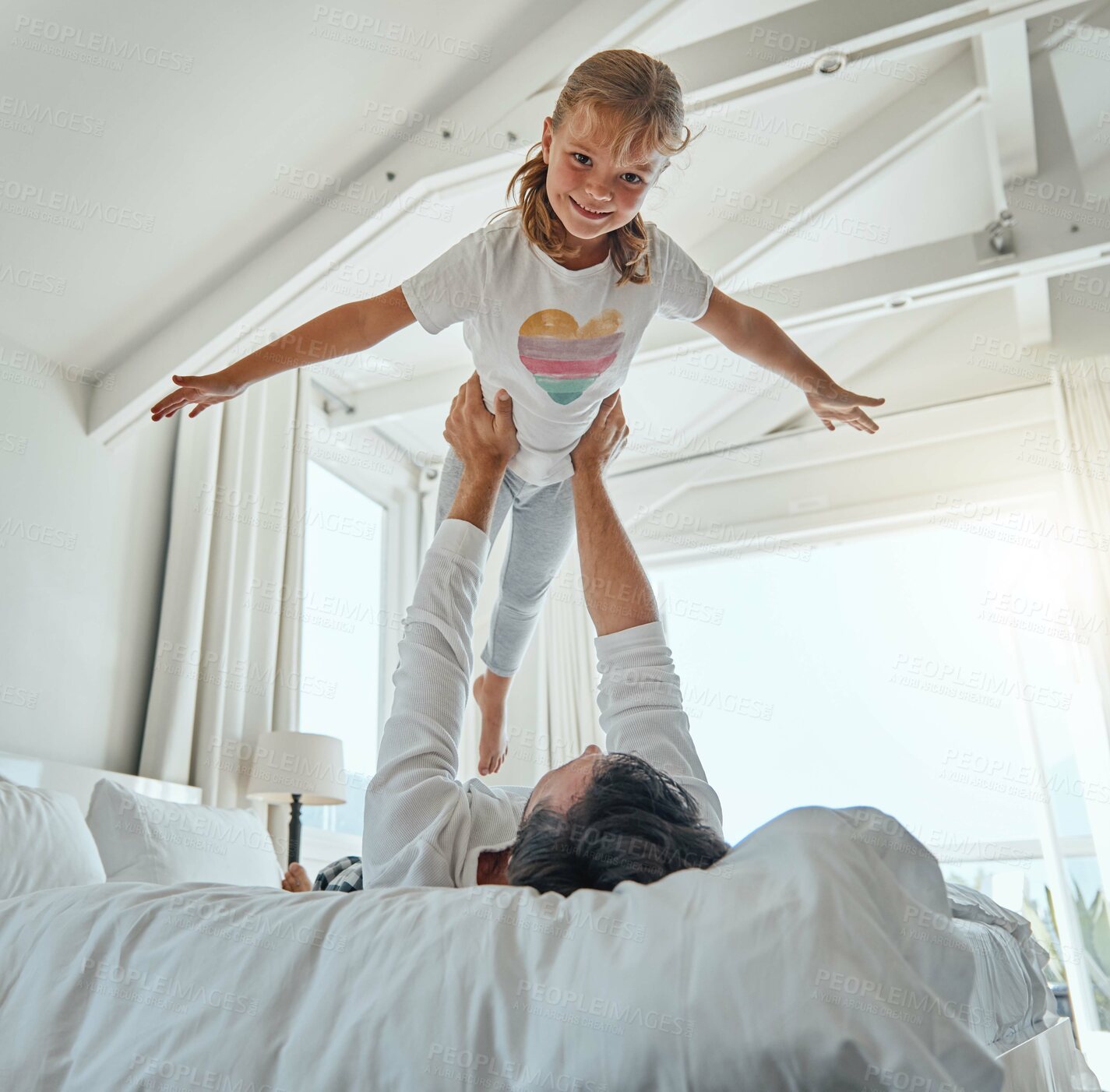 Buy stock photo Playful, bedroom and father holding his child while relaxing on the bed together in their home. Happy, smile and portrait of girl kid playing, resting and bonding with her dad in the room of a house.