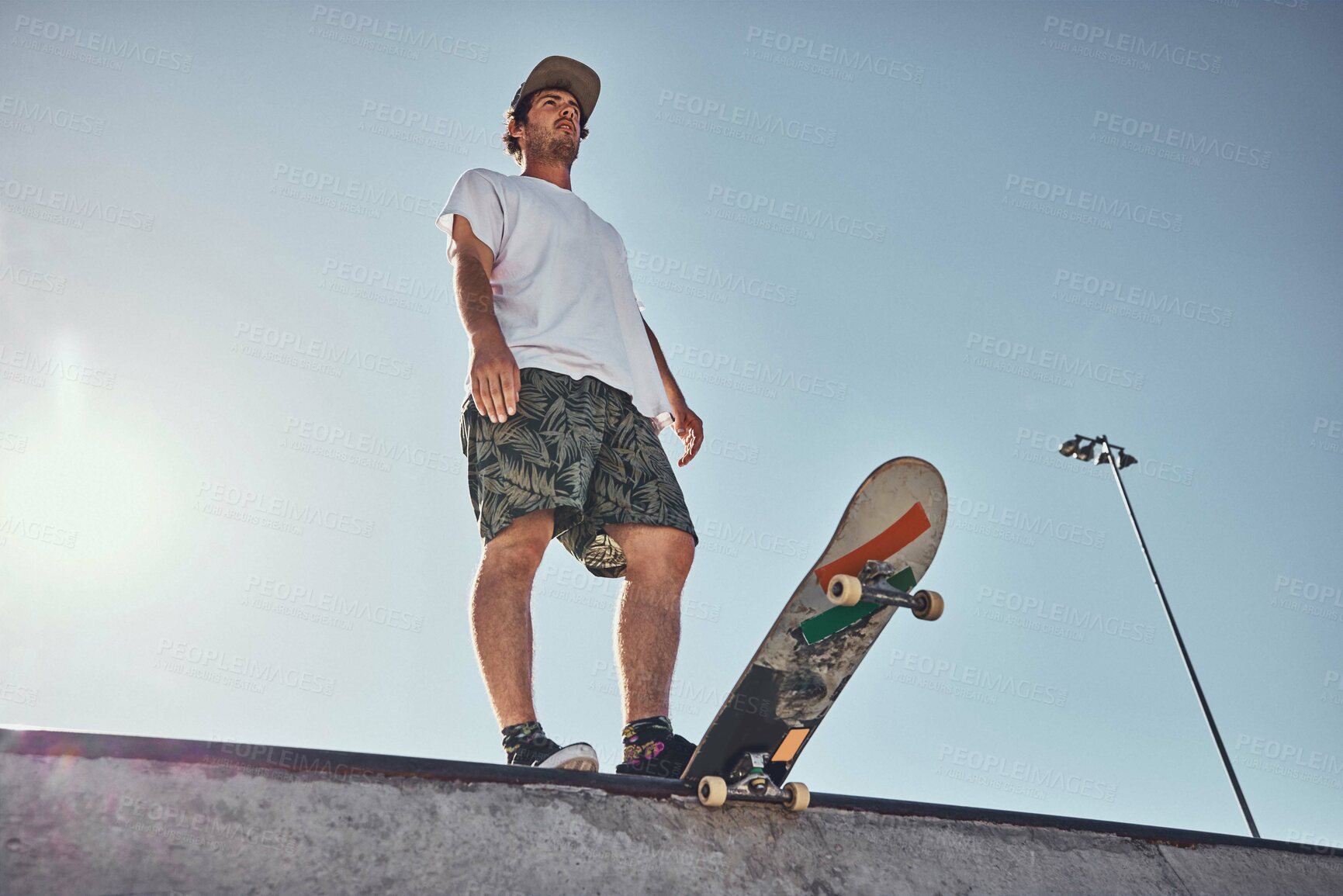 Buy stock photo Sports, skater and low angle of man on ramp preparing for action stunt, trick or practice in city. Thinking, skateboarding and male skateboarder getting ready for training or workout at a skate park
