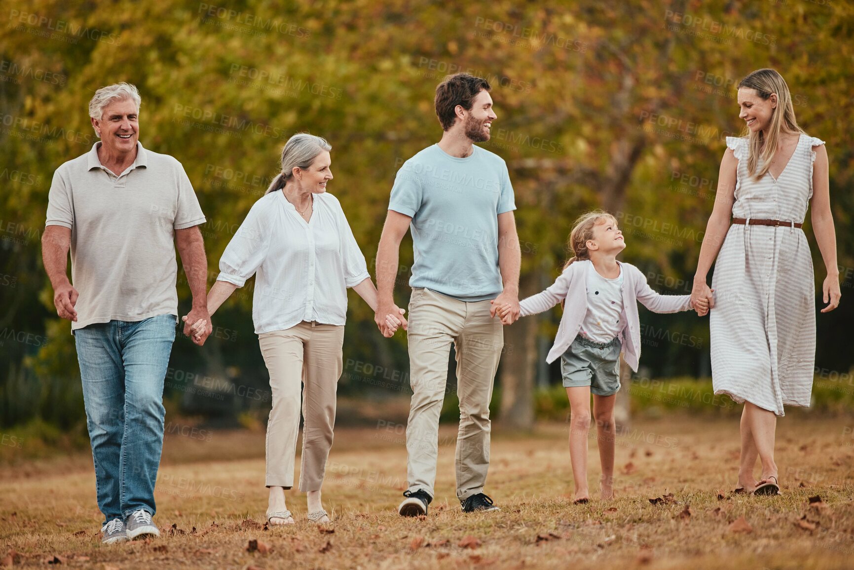 Buy stock photo Family walk, holding hands and park with smile, love and bonding with grandparents, kids or happiness. Happy family, walking or relax outdoor on nature adventure by trees, woods or forest