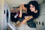Top view, laundry cleaning and woman by washing machine in home getting ready to wash clothing. Spring cleaning, hygiene and portrait of happy female sitting on floor preparing for housework alone.