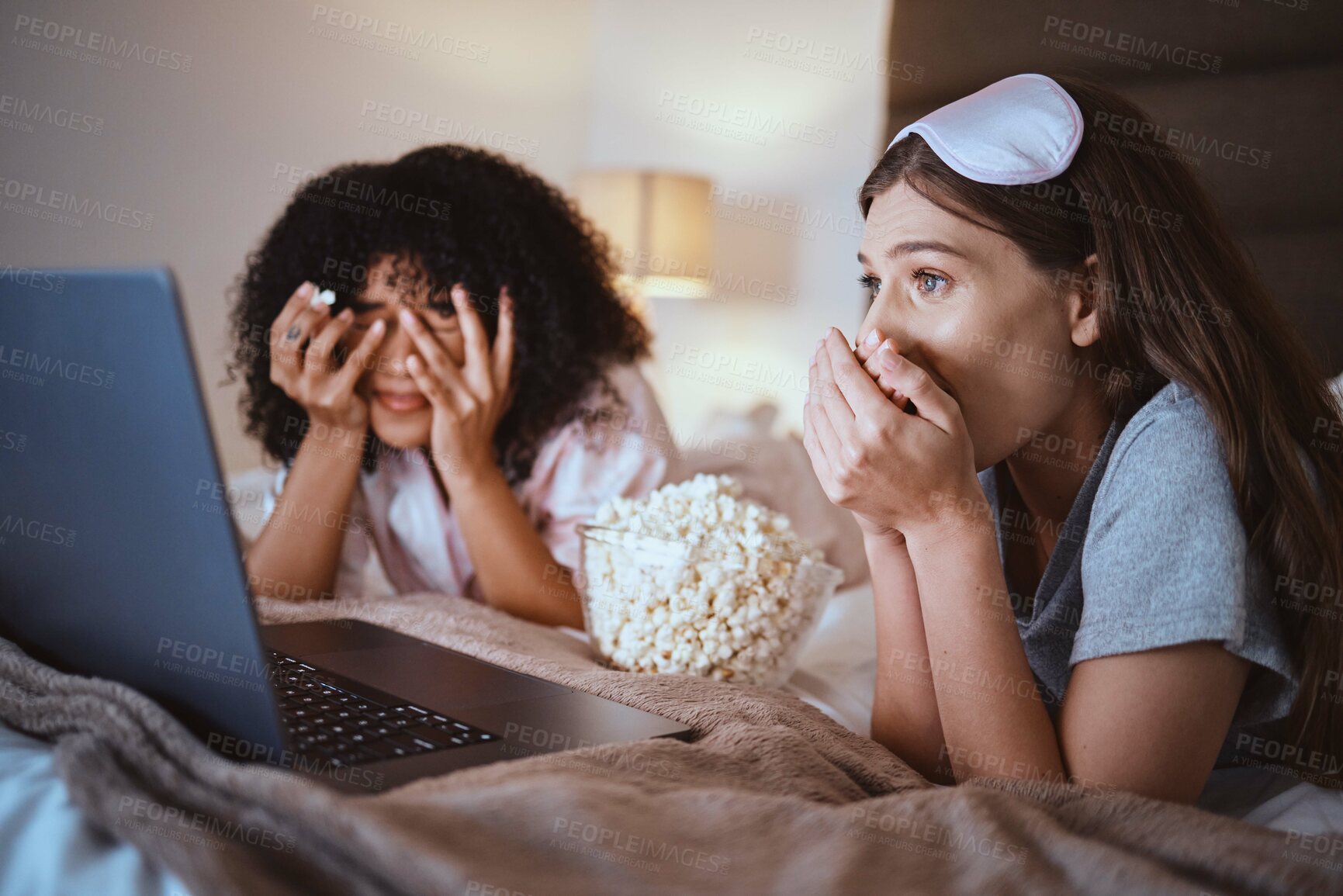 Buy stock photo Laptop, movie and horror with friends and popcorn in bedroom for sleepover, bonding and streaming. Technology, internet and relax with shocked women at night for cinema, subscription or entertainment