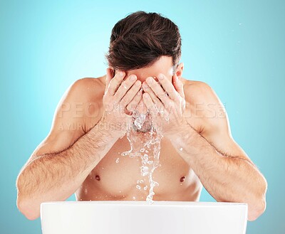Water, skincare and man with hands on face, morning cleaning treatment isolated on blue background. Facial hygiene, splash and male model grooming for health, wellness and clean skin care in studio.