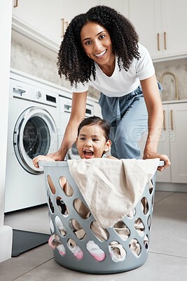 Buy stock photo Portrait of a mother with her kid in a laundry basket at their home while washing clothes together. Happiness, housework and face of young woman having fun with girl kid while cleaning the house.