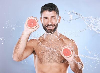Buy stock photo Grapefruit, water splash and man on blue background for wellness benefits, beauty and skincare. Male model, portrait and citrus fruits for vitamin c cosmetics, detox and nutrition for healthy shower