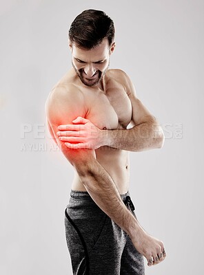 Tense, looking and a man with arm pain and muscle injury isolated on a grey studio background. Emergency, broken bone and person touching a painful, inflamed and hurt area in the body on a backdrop