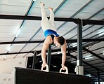 Man, acrobat and gymnastics upside down in balance for fitness practice, training or workout at gym. Professional male gymnast holding up body weight in the air for athletics or strength exercise