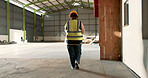 Warehouse, back of woman and engineer walking at empty industrial plant, manufacturing production or construction. Factory, rear view and worker or technician check storage, distribution or logistics