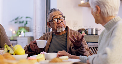 Buy stock photo Senior couple, drinking coffee and conversation at home, discussion and talking at dinner table. Elderly people, communication and speaking at night, meal and eating food together, talk and bonding