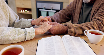 Buy stock photo Bible study, senior couple and holding hands for praying, religion and closeup in home for mindfulness. Elderly person, book and hope for peace, gratitude or connection to God, holy spirit or faith
