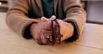 Hands, rosary and cross with closeup for religion, peace and hope at desk, home or praying for worship. Person, crucifix and jewelry for faith, mindfulness and connection to holy spirit, Jesus or God