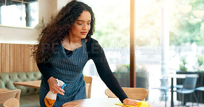 Waitress, woman and cleaning table in restaurant for dust, bacteria and dirt with cloth, spray or detergent. Barista, person and wipe wooden furniture in coffee shop or cafe with chemical liquid