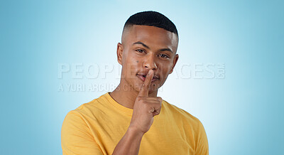 Buy stock photo Man, portrait and finger on lips for silence sign, secret deal or studio for promotion by blue background. Person, hand and cover mouth with icon, whisper and gossip for quiet voice, news or drama