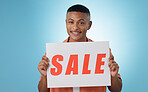 Portrait, sale sign or happy man by offer, discount deal or launch on studio space or logo advertising. Show, smile or person with board for message, marketing or promotion card on blue background