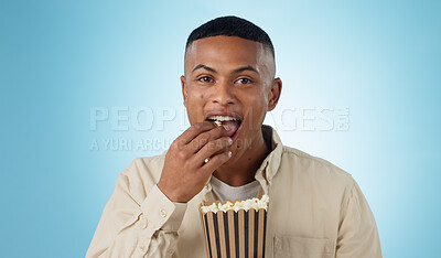Buy stock photo Portrait, happy man and popcorn for cinema in studio on blue background for entertainment mockup. Male model, eating and hungry with delicious, snack and food for watching, television and theatre