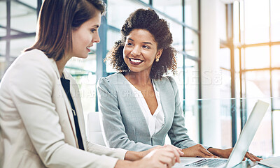 Buy stock photo Shot of two young businesswomen using a laptop together at work