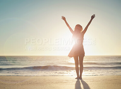 Buy stock photo Rearview shot of a woman posing with her arms outstretched at the beach
