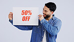 Happy man, sign and half price in discount, promotion or banner against a gray studio background. Male person or model smile with billboard or poster for advertising or marketing store sale or promo